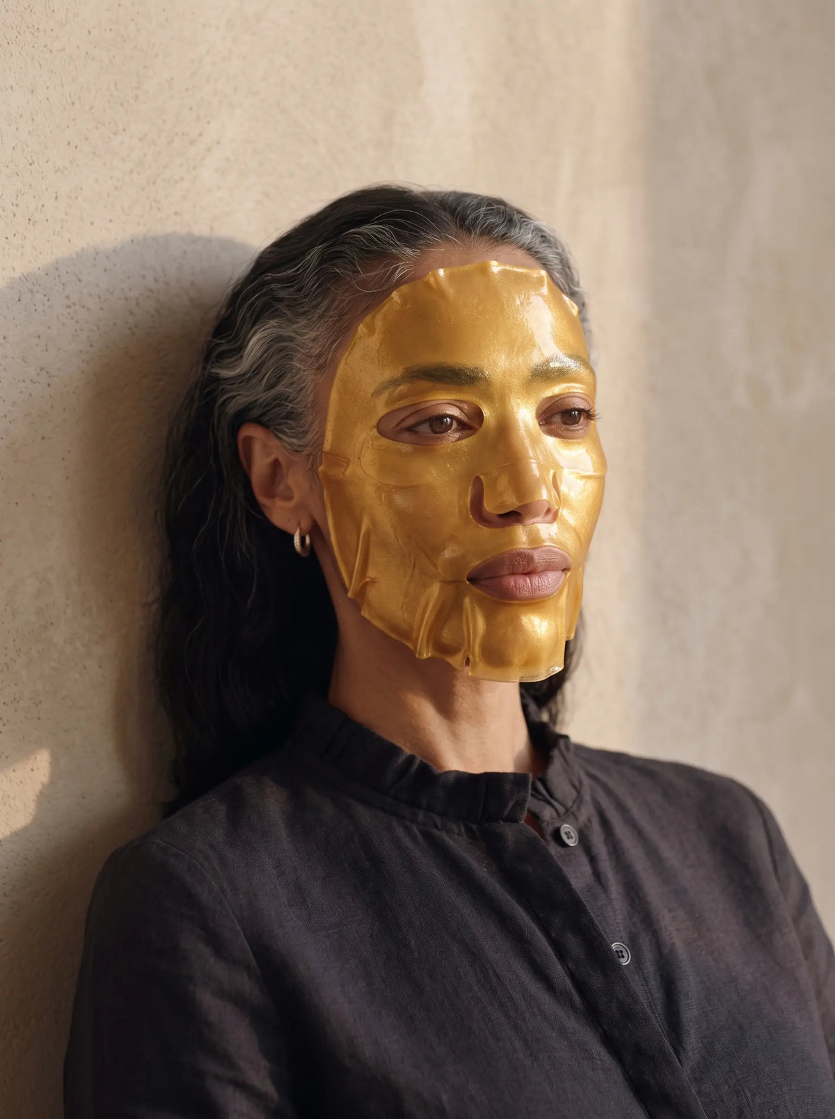 Mujer utilizando una mascarilla facial de colágeno dorado.