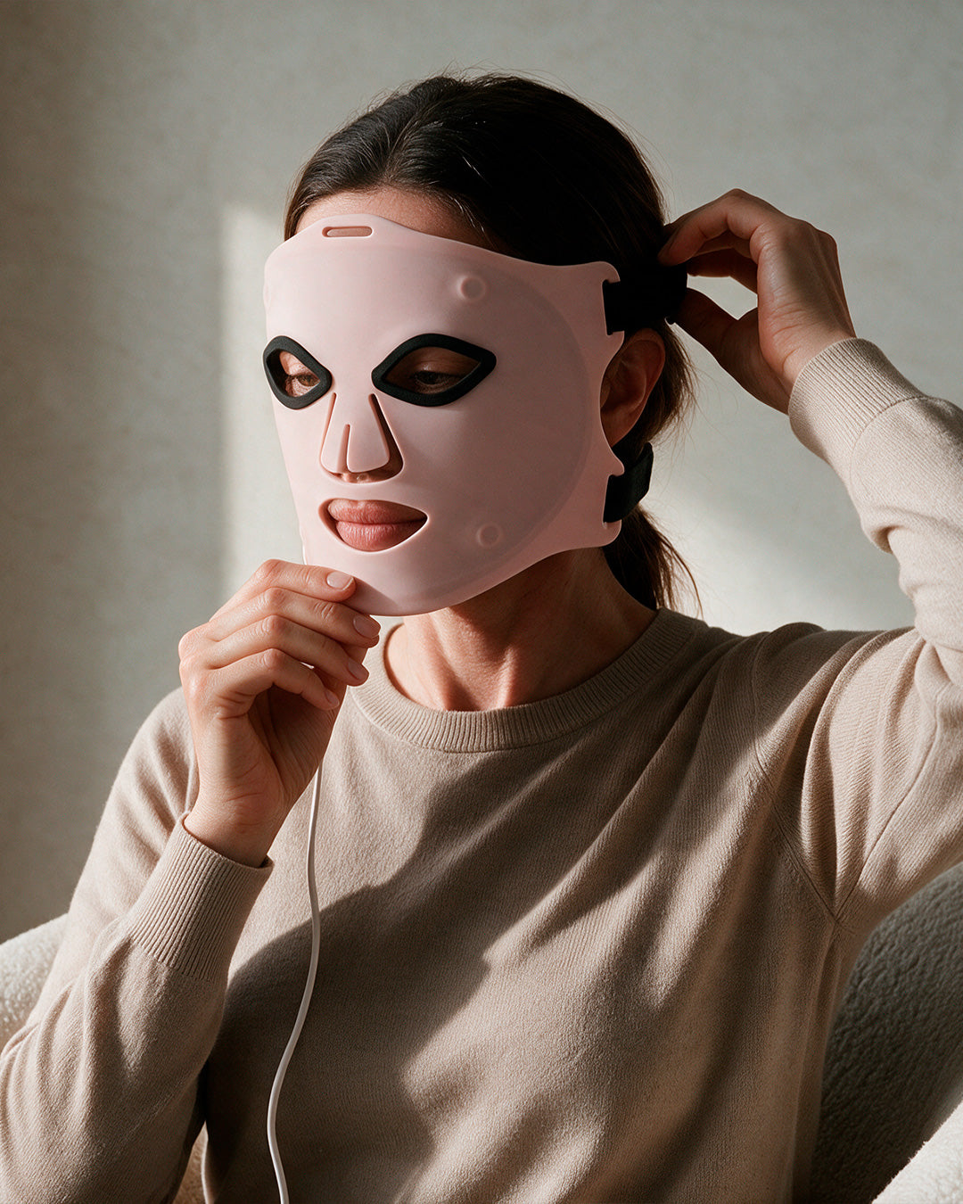Mujer colocándose la máscara LED facial Saglou en casa, con luz natural